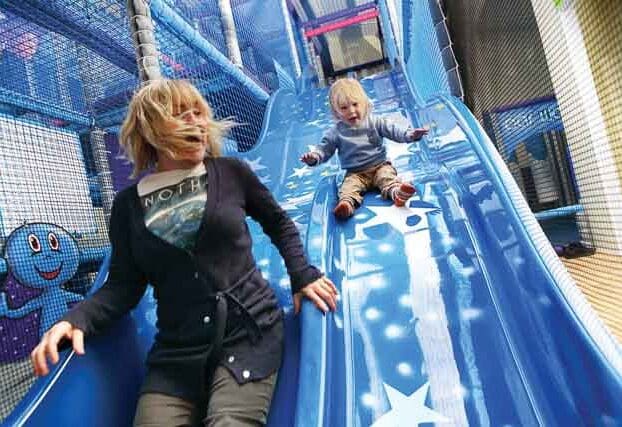 Adult and toddler sliding together at Planet Play inside The Milky Way Adventure Park, North Devon